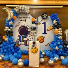 We created an out-of-this-world astronaut theme for Nick's first birthday. The decor includes a custom space backdrop, balloon columns in blue, silver, and black, and special foil balloons like a crescent moon and an astronaut.