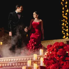 The grand entrance. For this reception, the couple descended a staircase lined with a carpet of red flowers and hundreds of glowing candles, creating a path of pure romance and drama.