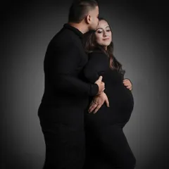 A classic and powerful portrait against a dark backdrop. The focus is entirely on the couple's embrace and the beautiful silhouette of the baby bump.