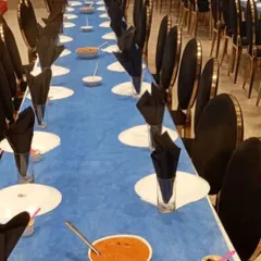A long view of our formal dining setup. The striking blue and black theme, with neatly folded napkins and pre-set dishes, shows our ability to execute a sophisticated and large-scale seated dinner service.