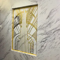 To make a memorable first impression, we created this Art Deco-inspired partition for an entryway. The custom-designed geometric pattern in gold and black metal set against a marble-finish wall adds a touch of timeless glamour.