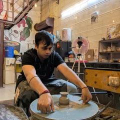 A participant is completely focused as he shapes a small vase on the pottery wheel. You can see the concentration and care that goes into learning this new skill.