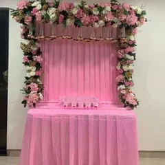A beautiful all-pink themed mandap decoration. The setup features a full arch of pink and white flowers over a matching pink draped table, creating a soft and devotional ambiance.