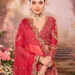 A beautiful editorial shot featuring a model in a red bridal outfit. The sleek bun, soft bronze makeup, and dreamy floral background create a timeless and artistic image.