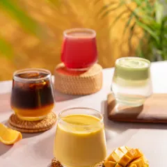 A colourful lineup of summer drinks from Blue Tokai Coffee. The bright, sunny lighting and tropical background create a refreshing and cheerful vibe.