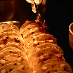 A chef's gloved hand uses tongs to generously fill a warm, freshly made tortilla at our live taco station. This close-up shot shows the care and attention that goes into crafting each individual taco for your guests.