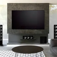This modern living room features a full KEF surround sound system. The slim tower speakers, matching center channel, and subwoofer are arranged to provide an immersive soundstage for movies, all while maintaining a clean, minimalist look.