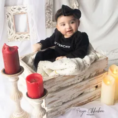 Dressed in style and glowing with charm. This cozy studio setup with a rustic crate, soft blanket, and warm candlelight creates a sophisticated and sweet portrait.