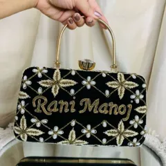 For a classic and elegant look, this black velvet clutch was customized for 'Rani' and 'Manoj'. The gold and white floral embroidery stands out beautifully against the dark fabric.