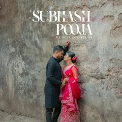 A romantic pre-wedding portrait with a rustic, old-world charm. The weathered wall provides a beautiful texture and backdrop for the couple, who are dressed in elegant traditional attire.