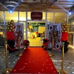 Roll out the red carpet for an unforgettable celebration. This Casino Night themed party entrance features larger-than-life playing cards, a red carpet walkway, and gold stanchions, setting a glamorous and high-energy tone for an adult birthday or corporate event.