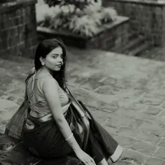 An elegant black and white portrait on stone steps. The model's over-the-shoulder glance and the beautiful drape of her saree create a classic and sophisticated composition.