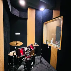 A view of our drum isolation booth from the main jam room. The glass window allows for clear sightlines between the drummer and the rest of the band, ensuring everyone stays in sync.