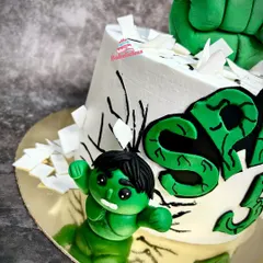 A side view focusing on the mini Hulk fondant figure, showing his determined expression and the "smashed" sugar shards around him.