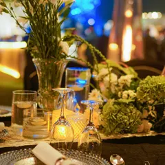 A place setting detail, with a silver-beaded charger plate, a neatly rolled napkin, and a crystal-clear wine glass, all glowing in the candlelight.