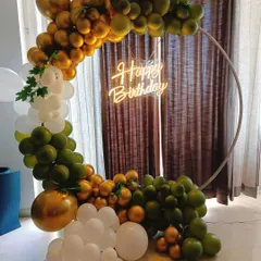 A modern and organic balloon arch on a ring frame for a birthday party. The combination of olive green, white, and chrome gold balloons creates a sophisticated and trendy look.
