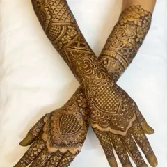 A beautiful crossed-arm pose showing the symmetry and detail in bride Sunera's full bridal henna. The patterns are designed to look beautiful from every angle.
