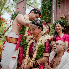 The groom performs a traditional ritual, surrounded by family, during a vibrant outdoor wedding ceremony.
