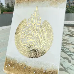 An outdoor shot to capture the natural light on this Ayat al-Kursi artwork. The intricate gold calligraphy is set on a white and sand-colored resin base, with scattered crystals that sparkle in the sun.