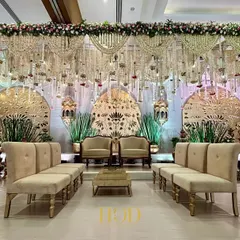 The stage is the heart of your celebration, and I make sure it's nothing short of spectacular. This expansive wedding reception stage features intricate golden laser-cut panels and cascading floral arrangements, creating a backdrop of pure opulence and grandeur.