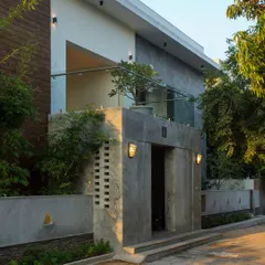 The entrance to Eco Terre features a bold, board-formed concrete finish and a `jaali` brick screen, introducing modern, textural materials while improving natural ventilation.