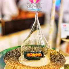 Presentation is key to the experience. Here, a delicate rose-infused baklava roll is presented under a glass cloche, creating a moment of drama and elegance for guests at a luxury wedding buffet.
