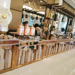 A complete view of the contemporary buffet setup, showing the stylish arrangement of food containers and decorative elements. The mirrored surfaces reflect the venue's lighting, adding to the ambiance.