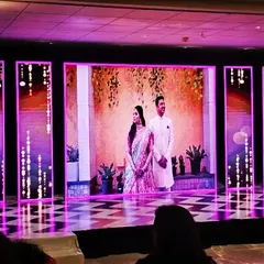 An impressive LED stage setup for a Sangeet night. The multiple screens display dynamic graphics and photos of the couple, creating a personalized and high-tech backdrop for the performances.