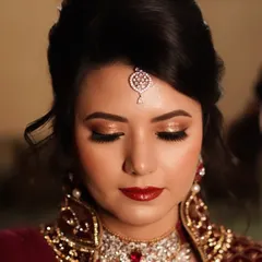 A truly classic bridal party look. The combination of luminous gold glitter on the eyes and a rich, glossy red lip creates a feeling of opulence and sophistication, perfect for an evening reception.