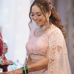 A candid moment of joy from her engagement ceremony. Her makeup features a soft pink shimmer on the eyes, and her hair is styled in a curly ponytail with delicate pearl accessories.