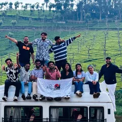 The group posing on top of our traveller van with the beautiful Ooty tea estates in the background.