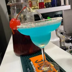 A vibrant Blue Lagoon cocktail, expertly crafted and ready to be served. We pride ourselves on creating visually stunning drinks using premium spirits and fresh ingredients, like this one with a classic sugar-rimmed margarita glass and cherry garnish.