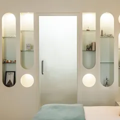 Storage and display were key in this kids' room. We designed a wall unit with a playful mix of circular and arched niches, all back-lit to highlight treasured toys and books. A frosted glass door provides privacy while maintaining the room's light and airy feel.