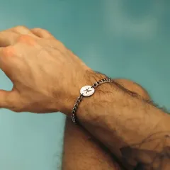 A man wearing my silver chain-link bracelet featuring a custom-engraved disc with the Pisces zodiac symbol. This style offers a modern alternative to the classic cuff.