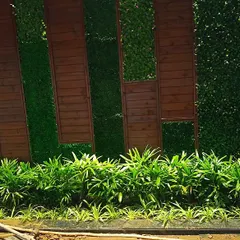 Here is another example of combining artificial greenery with wood panels. This design uses the wood to frame the green sections, creating a clean, architectural look complemented by a bed of real plants at the base.