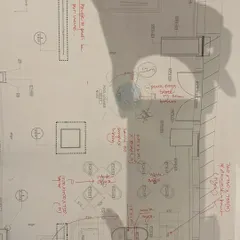 The shadow of a hand over a detailed architectural drawing. This image symbolizes the human touch and creative thought that animates every line and informs every design decision.