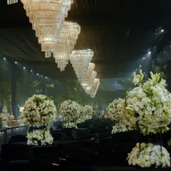 The seating for this cocktail event featured tables draped in black sequin linens, topped with large bouquets of white roses. Overhead, a line of magnificent crystal chandeliers cast a glittering glow over the entire space.