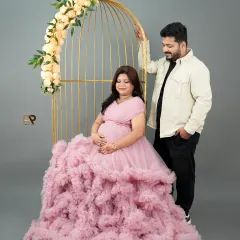 A vision in pink. This portrait uses a golden birdcage prop and a voluminous ruffled gown to create a whimsical and highly stylized maternity photo.