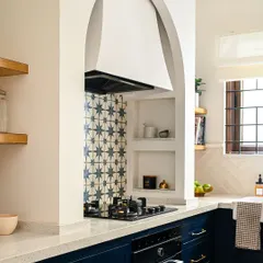 This close-up shows the custom arched chimney hood and the built-in nooks I designed to hold everyday cooking essentials. The patterned tile backsplash extends all the way to the ceiling, making a dramatic statement and adding a layer of beautiful detail to this Spanish-inspired kitchen design.