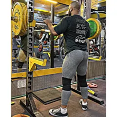 Setting up for a heavy squat in the rack. Wearing knee sleeves and a lifting belt provides support for maximal lifts, allowing you to push your limits safely.