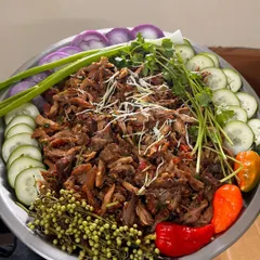 A large platter of my spicy chicken salad, also known as chicken singju, garnished with fresh herbs and chilies.
