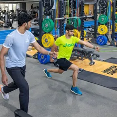 Our coach provides one-on-one guidance during a resistance band lunge, an exercise that improves stability and power in the running gait. We ensure proper form for maximum benefit.