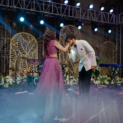 A classic, chivalrous moment during the couple's Sangeet dance performance, complete with stage smoke for a dreamy effect.