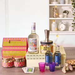 This modern gin-themed wedding hamper includes a bottle of Greater Than Gin, tonic water, a cocktail jigger, and snacks, all presented in vibrant, contemporary packaging.