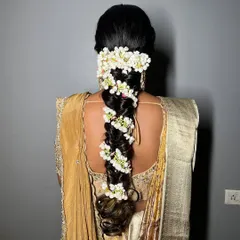 A stunning traditional South Indian bridal hairstyle. This long braid is adorned with fresh jasmine flowers (gajra), creating a fragrant and beautiful look for a baby shower.