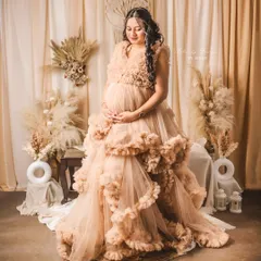 An expectant mother looking serene in a stunning, ruffled beige gown. This image highlights my boho-chic studio maternity sessions, complete with pampas grass and soft, natural styling.