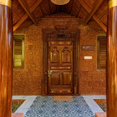 Detail is everything in architecture. This intricately carved wooden door, set against a rustic laterite brick wall and framed by traditional pillars, creates a grand and welcoming entrance for a resort project. It's a nod to timeless Indian craftsmanship.