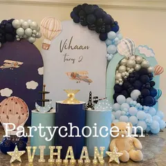 A vintage airplane and hot air balloon theme in shades of navy and light blue. This decoration includes arched backdrops, themed props, and a teddy bear pilot for a charming adventure in the sky.