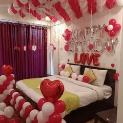 A romantic red and white balloon decoration for a birthday, featuring "Happy Birthday" and "LOVE" foil letters and heart-shaped balloons.