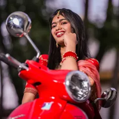The Vespa Bride. A close-up shot capturing the bride's joyful smile as she poses with the iconic red scooter, blending tradition with modern fun.